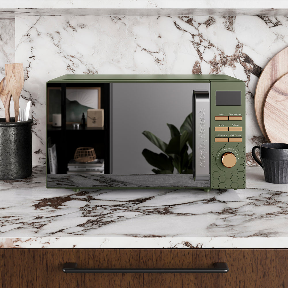 Green microwave oven on a marble countertop with a kitchen setting.