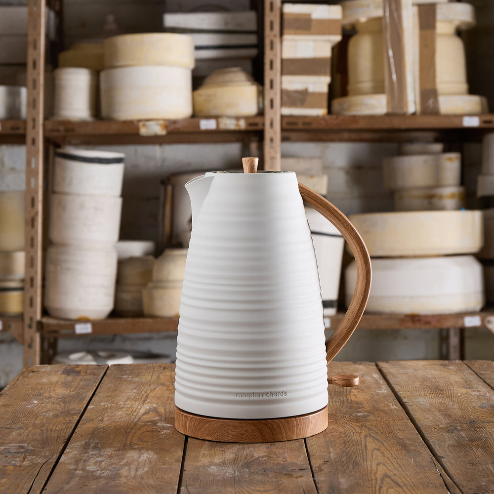 White electric kettle with wooden handle on a wooden table in a pottery