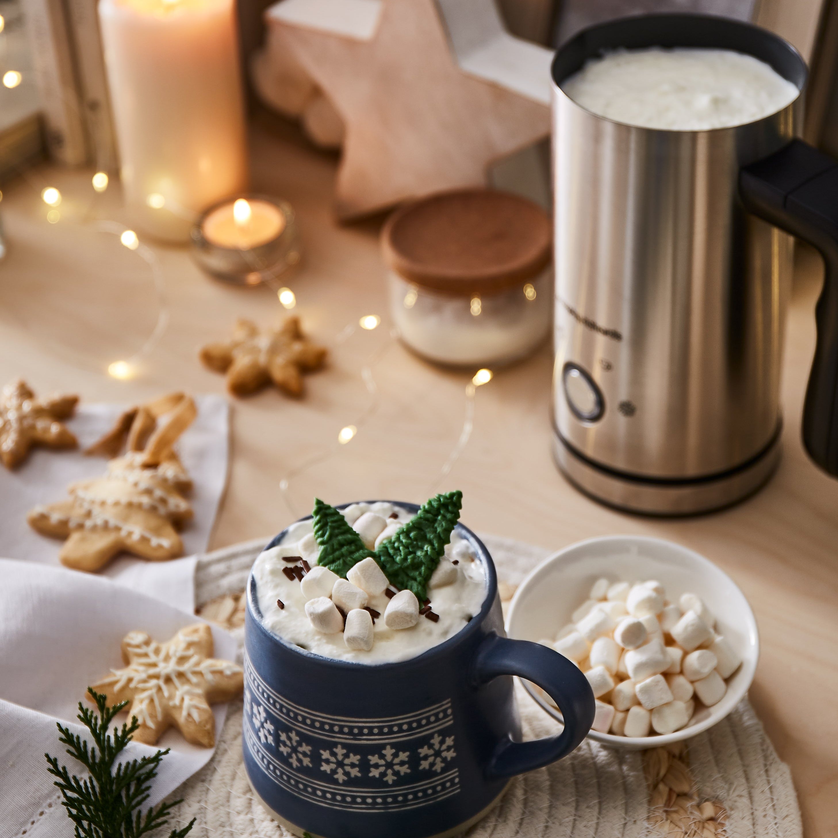 Hot chocolate with marshmallows in a blue mug on a festive table with cookies and the Morphy Richards milk frother.